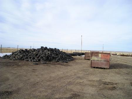 Large pile of used tires next to dumpster